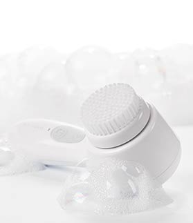 Skinvigorate Sonic™ Skin Care System from Mary Kay lying next to bubbles. 
