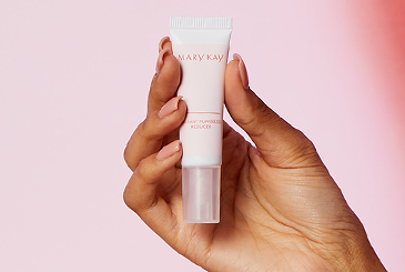 Una mano sostiene un tubo del Mary Kay® Instant Puffiness Reducer contra un fondo color rosa claro